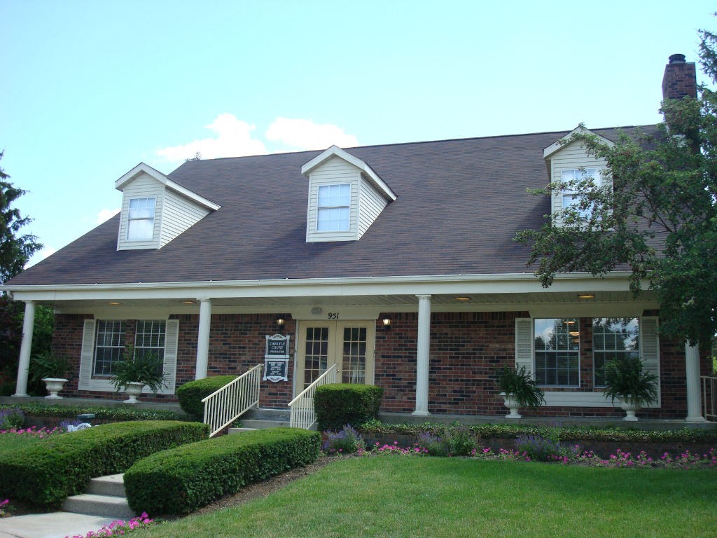 the front of a brick house with a porch and a lawn
