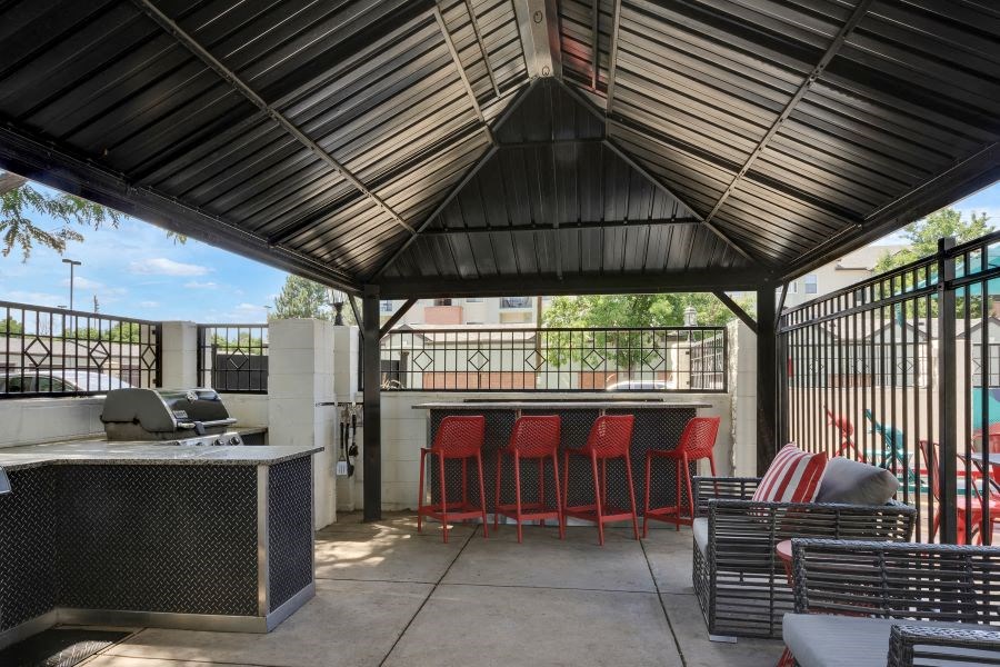 a patio with a bar and chairs and a grill