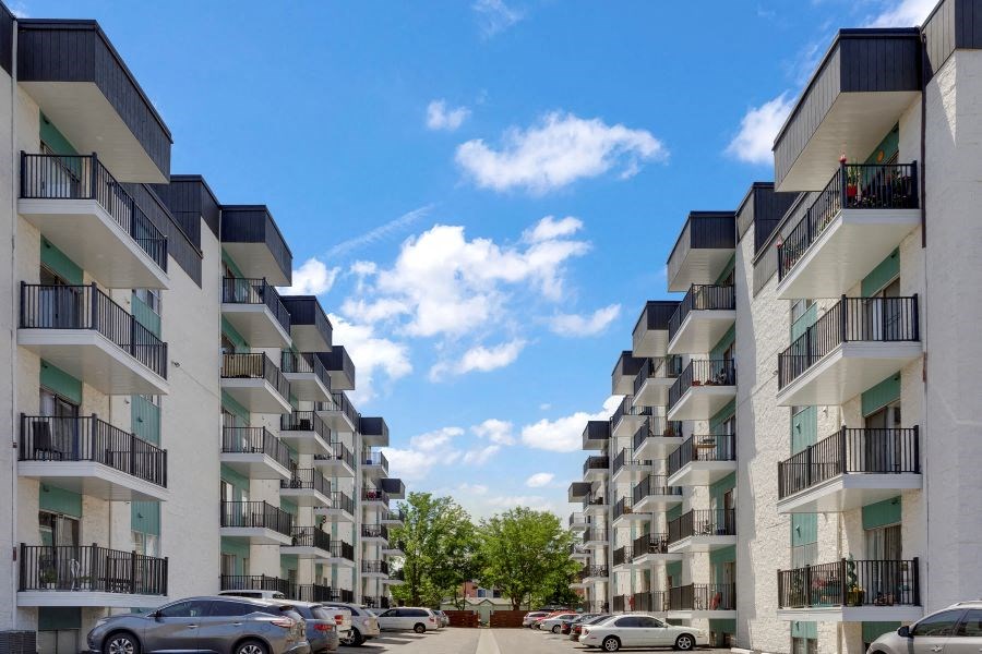 a row of apartment buildings with cars parked in a parking lot