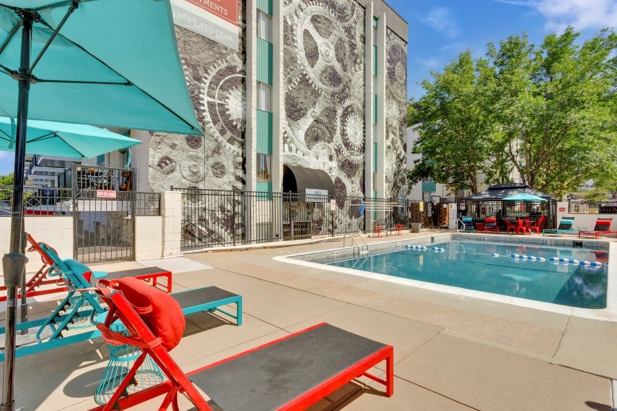 a swimming pool with chairs and umbrellas in front of a building