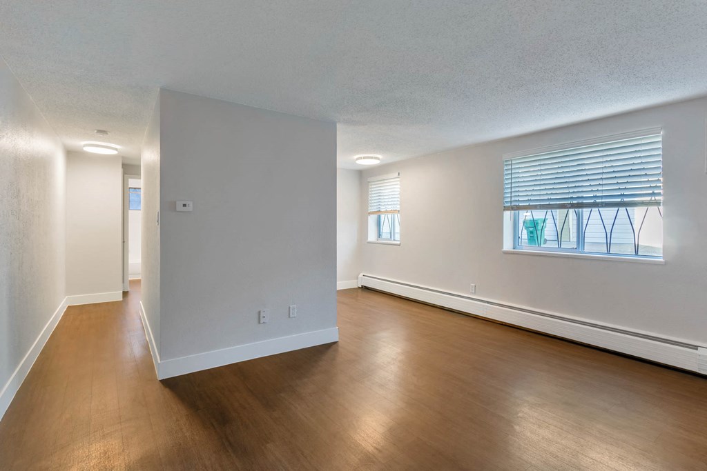 an empty living room and dining room with wood floors and a window