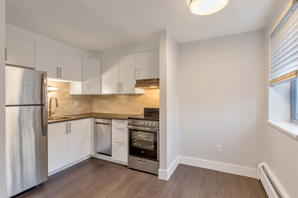 a renovated kitchen with white cabinets and stainless steel appliances