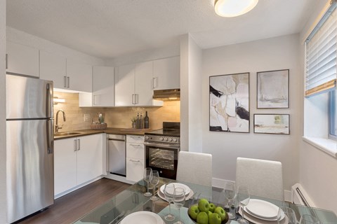 a kitchen and dining room with white cabinets and stainless steel appliances