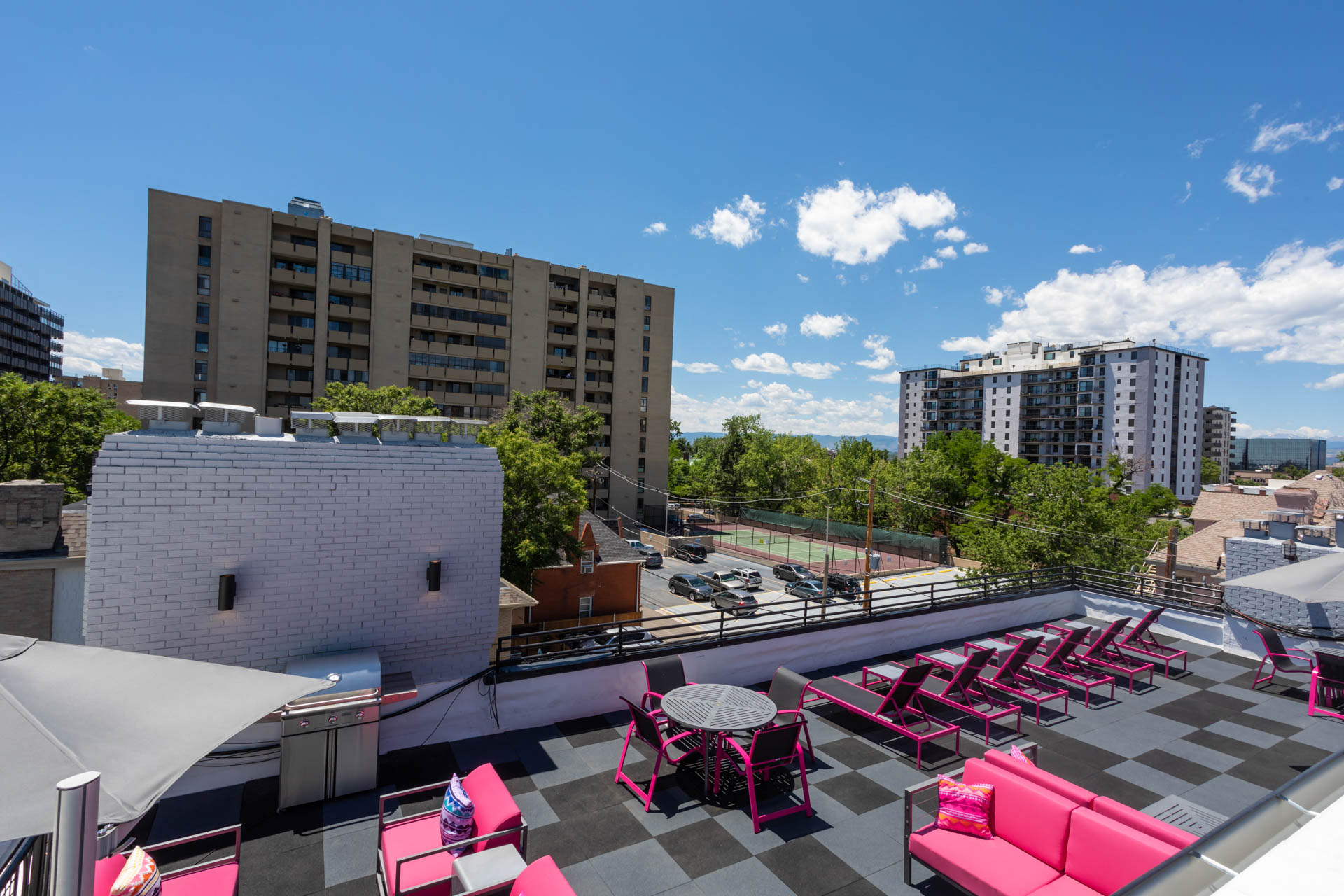a rooftop patio with pink chairs and tables and buildings