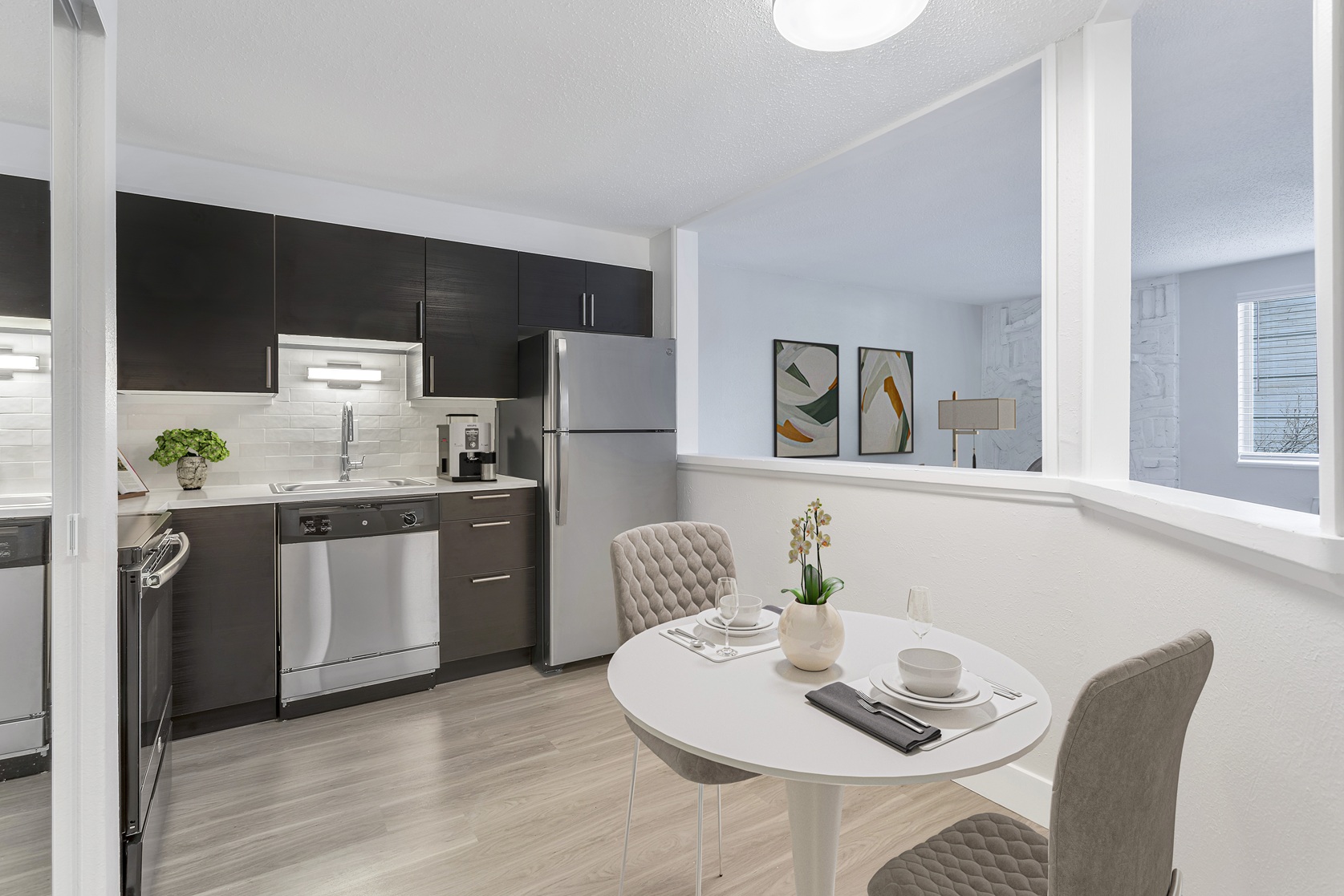 A modern kitchen with a dining table set for two.