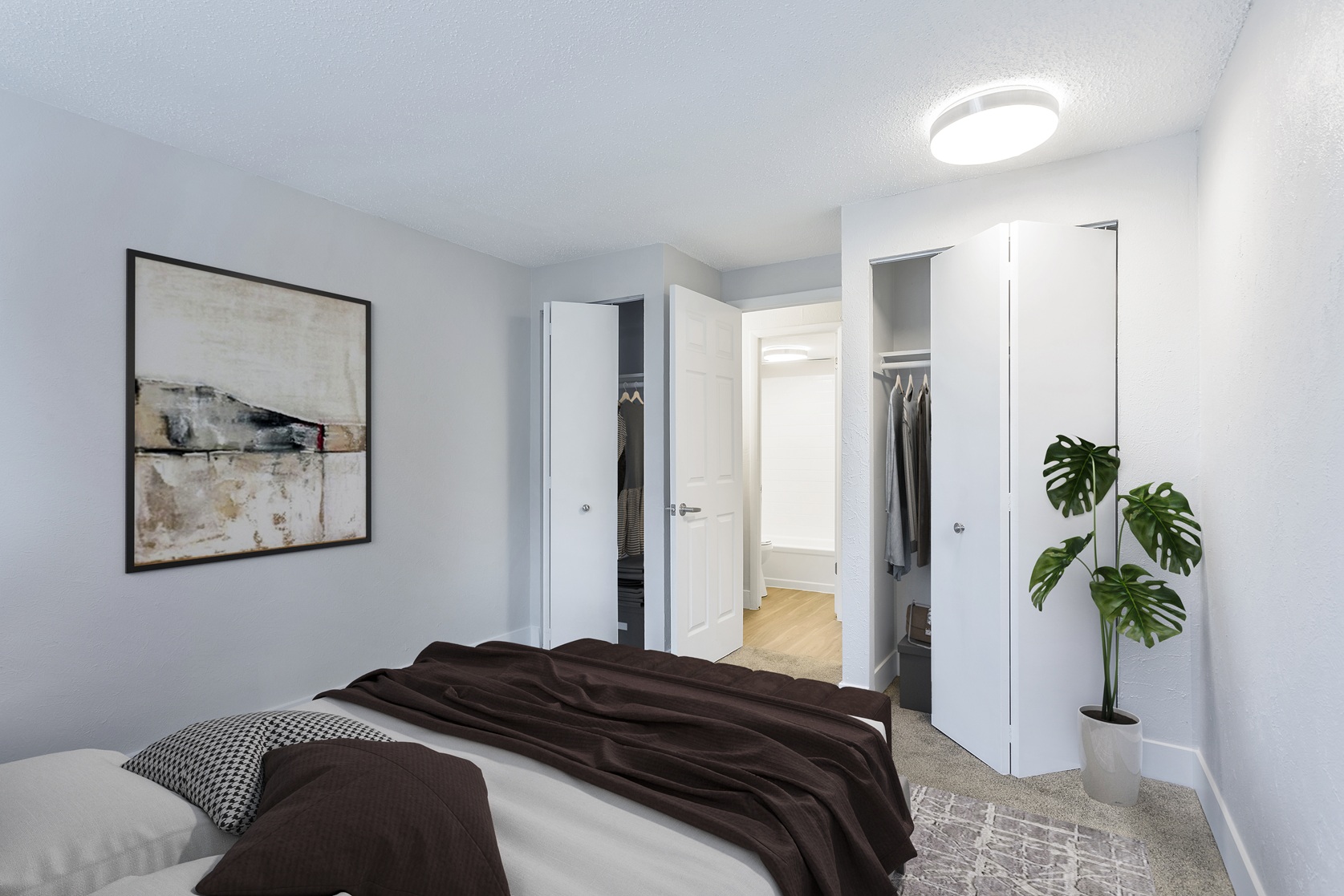 A bedroom with a bed, a plant, and a painting on the wall.