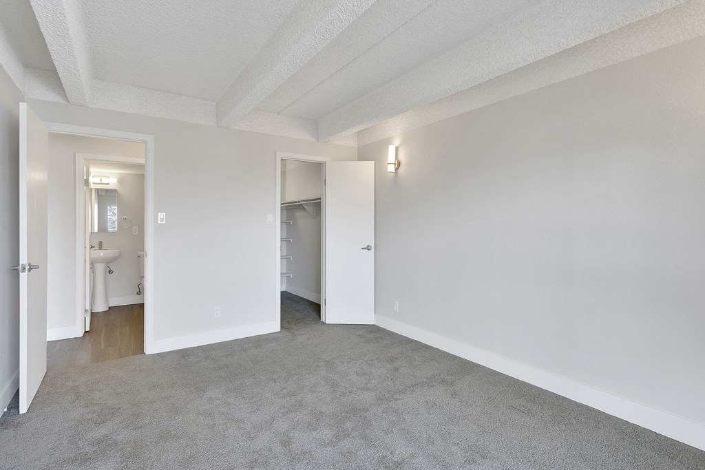 the living room of an apartment with carpet and white walls