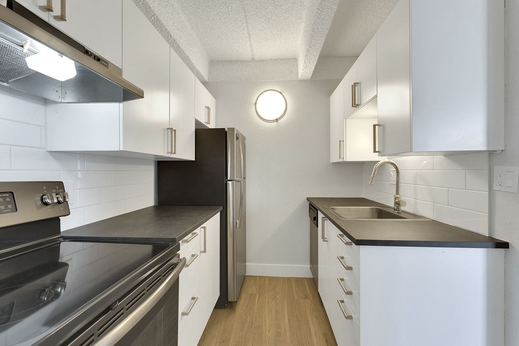 an empty kitchen with white cabinets and stainless steel appliances