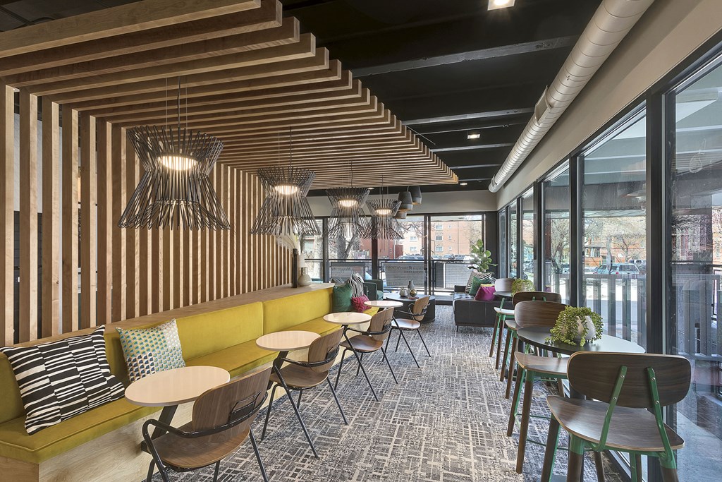 a lounge area with tables and chairs and a large window