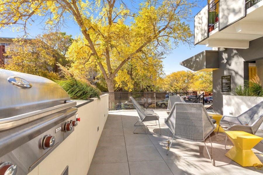a patio with tables and chairs and a barbecue grill