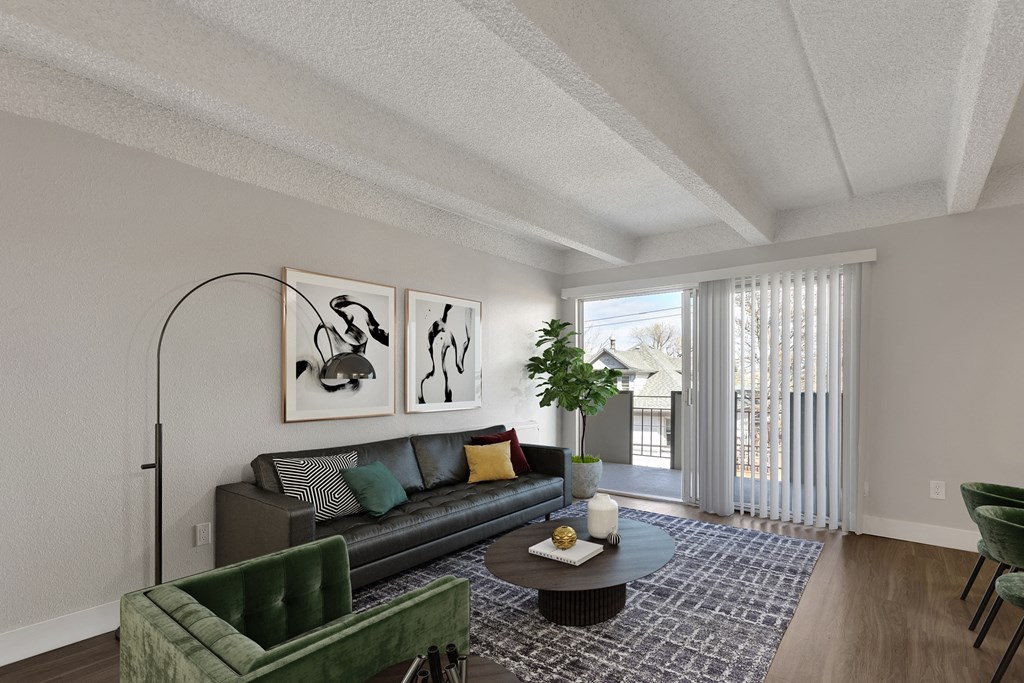 the living room of an apartment with a large window and a couch and chairs