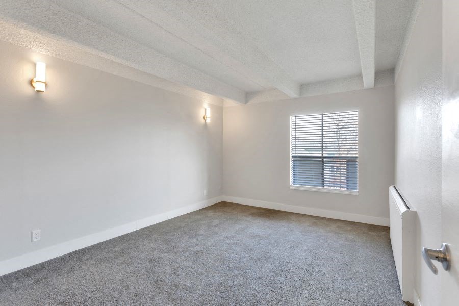 an empty living room with white walls and a window