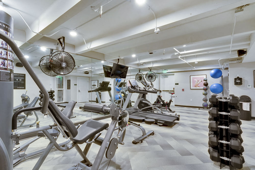 Full fitness center including treadmills, free wright dumbbells, cable machine, cardio equipment and full wall mirror.