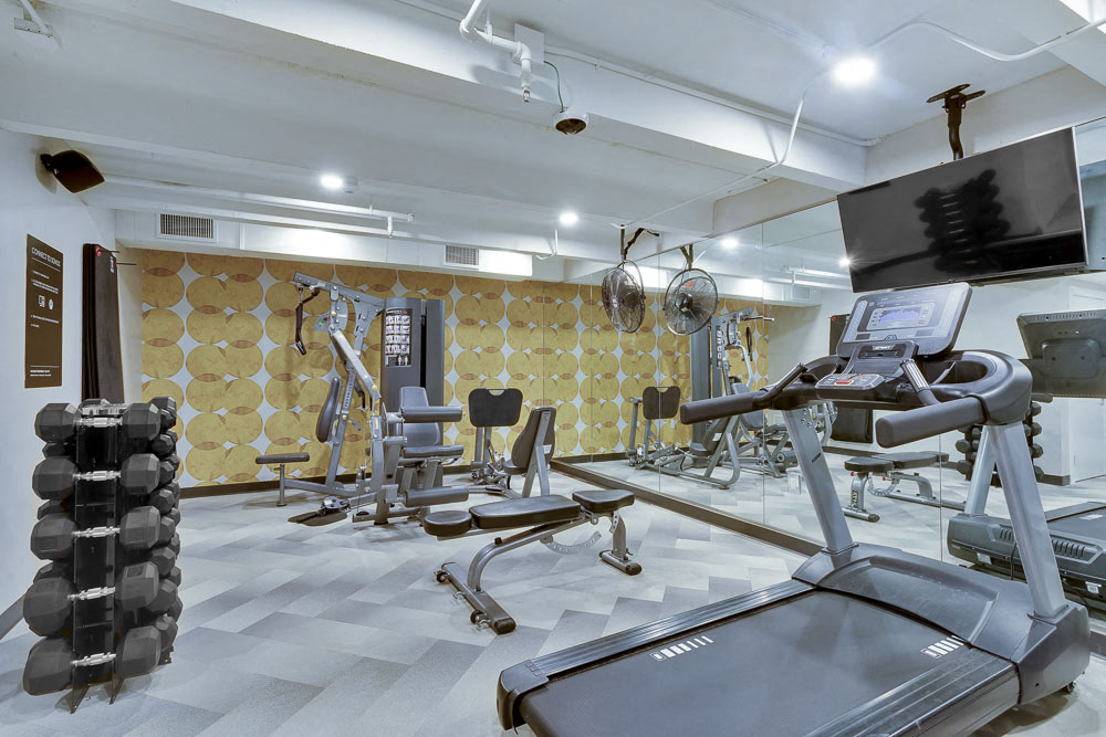 Full fitness center including treadmills, free wright dumbbells, cable machine, cardio equipment and full wall mirror.