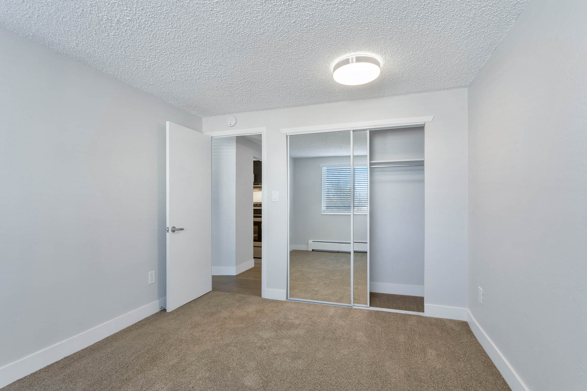 an empty living room with mirrored closet doors and a carpeted floor