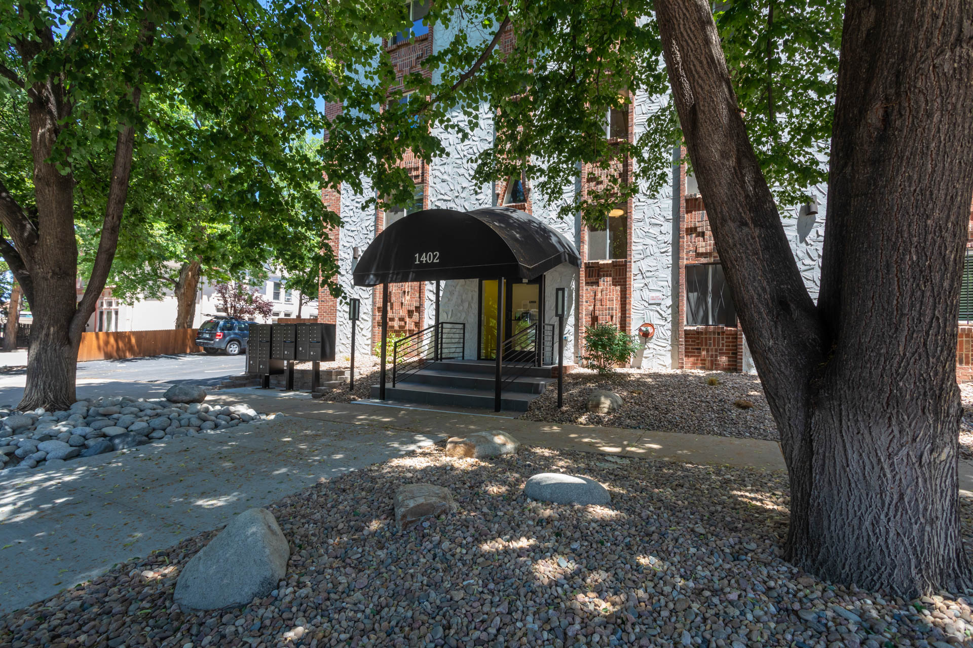 a building with a black awning and trees in front of it