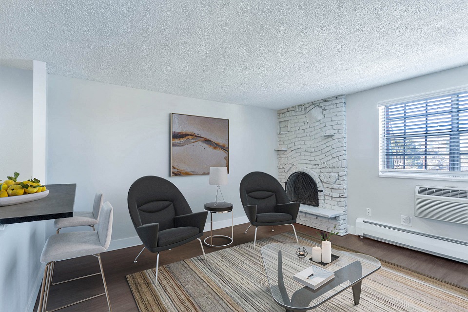 a living room with chairs and a table and a stone fireplace