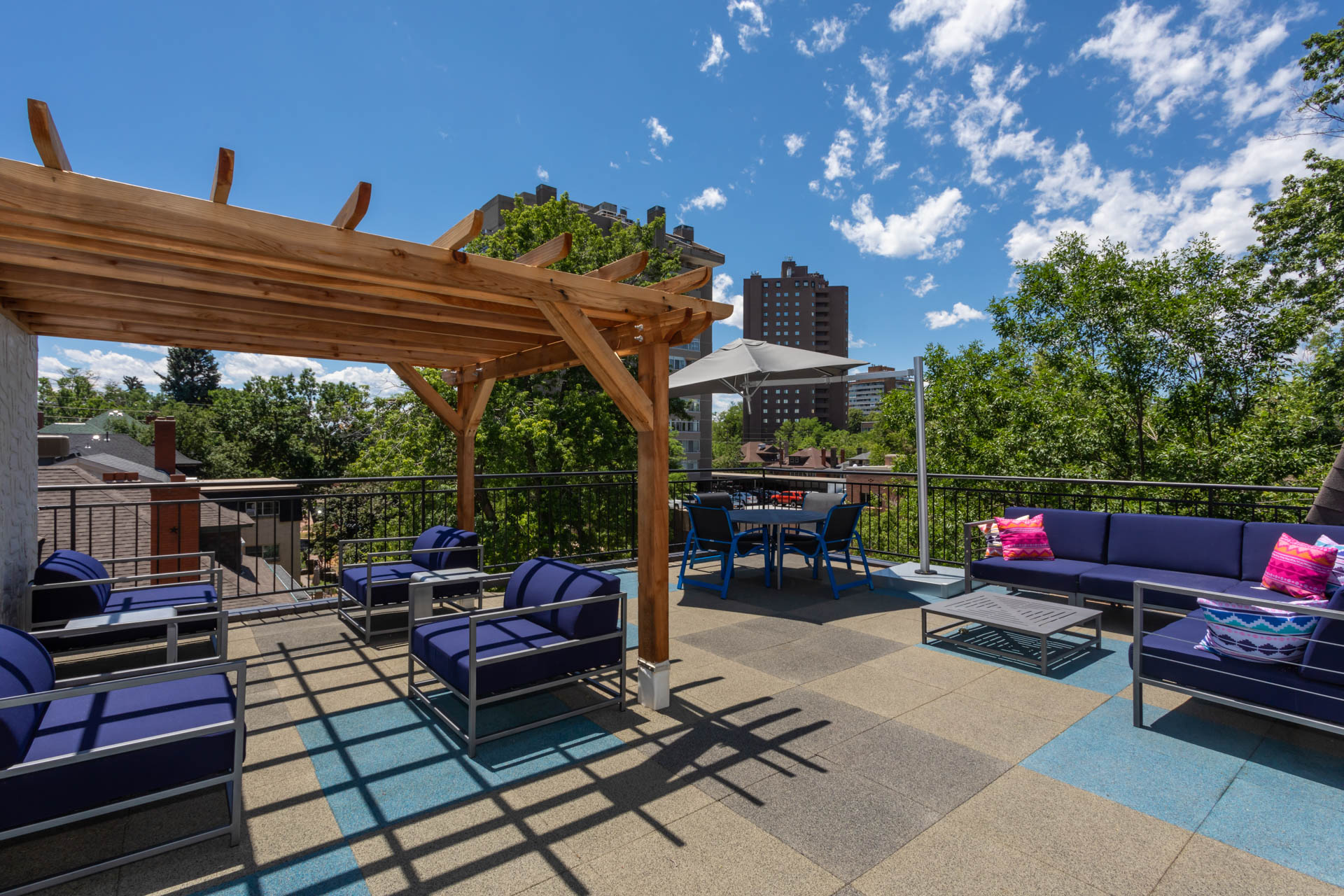 a rooftop patio with couches and tables and a pergola