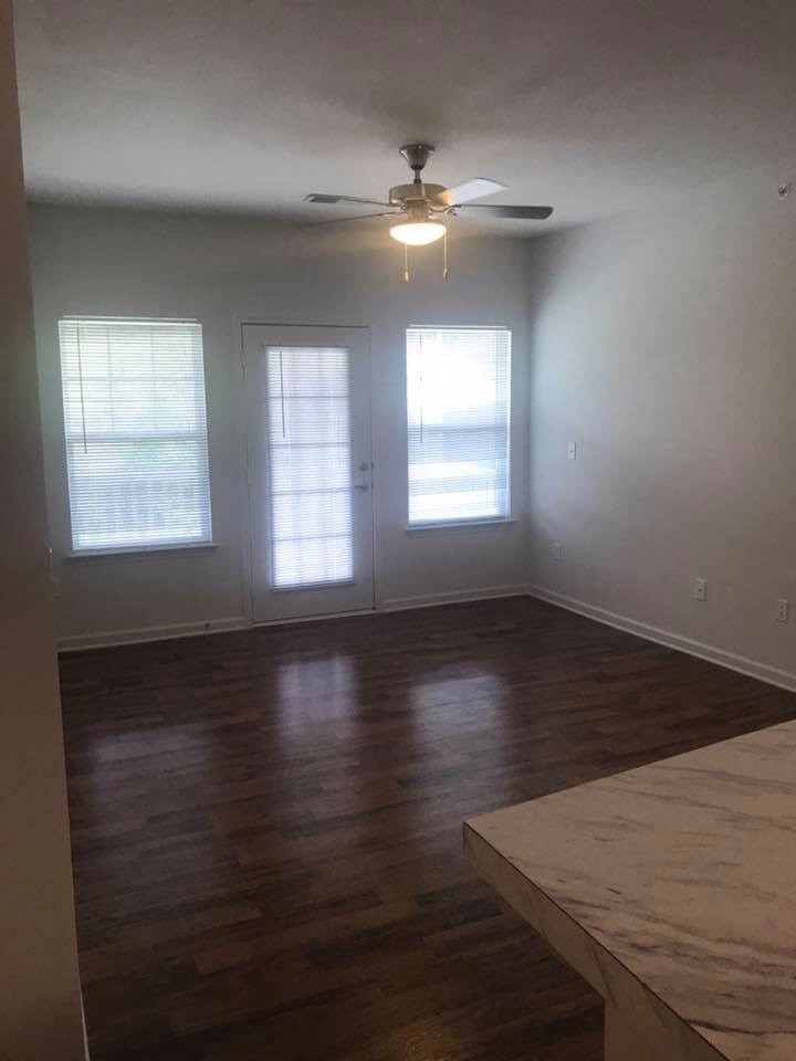 an empty living room with wood floors and a ceiling fan
