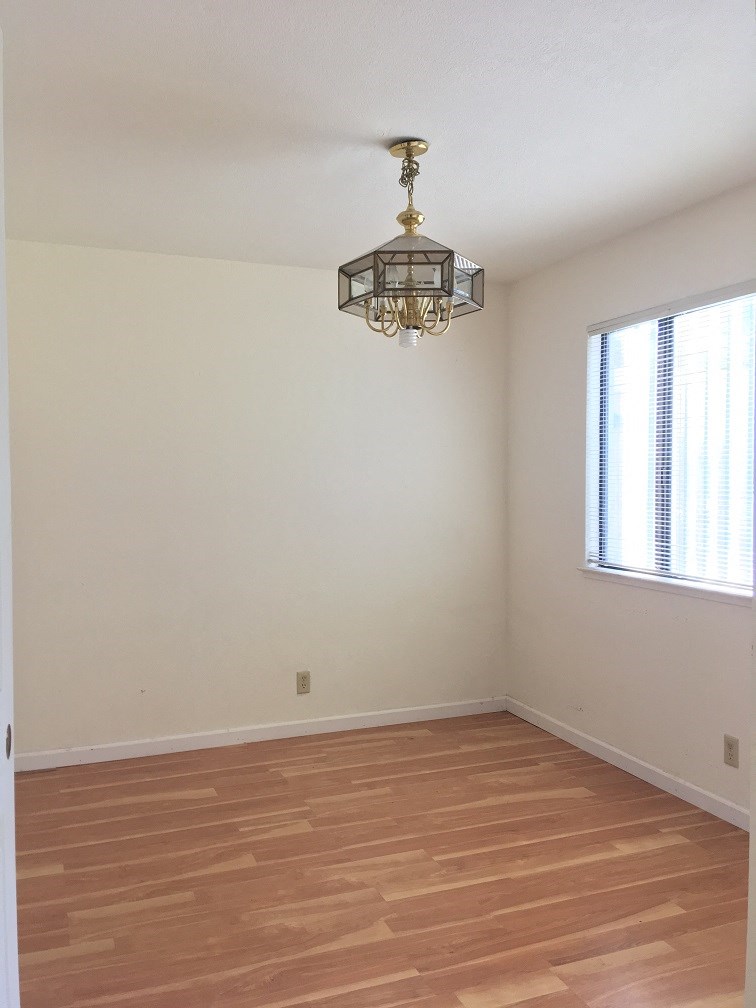 an empty living room with wooden floors and a chandelier