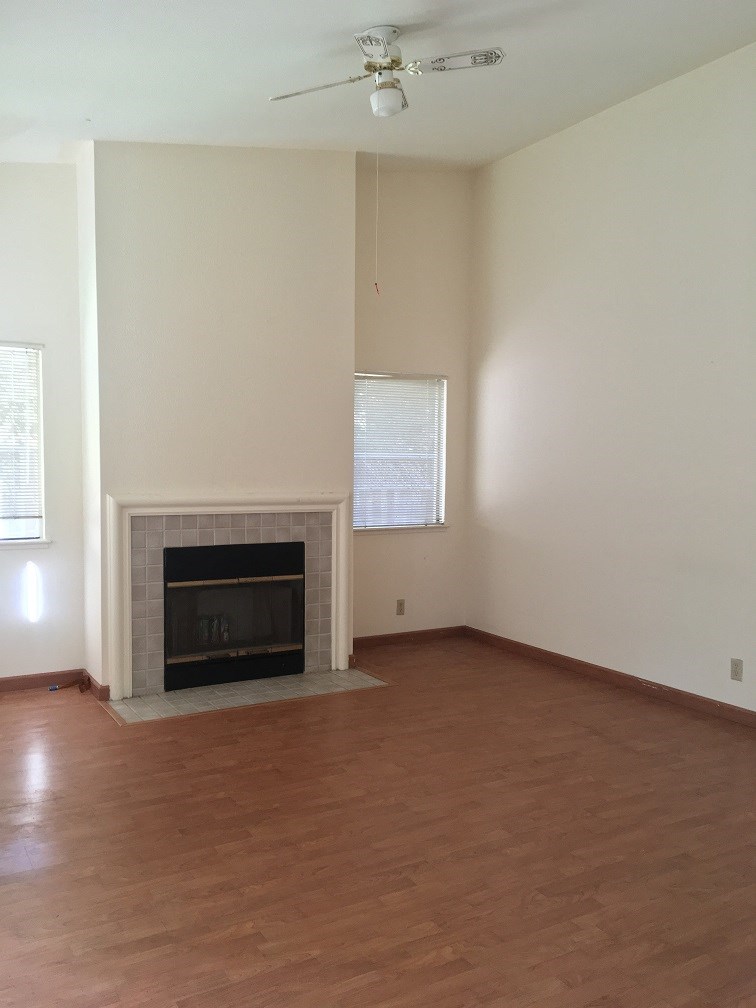 an empty living room with a fireplace and a wooden floor