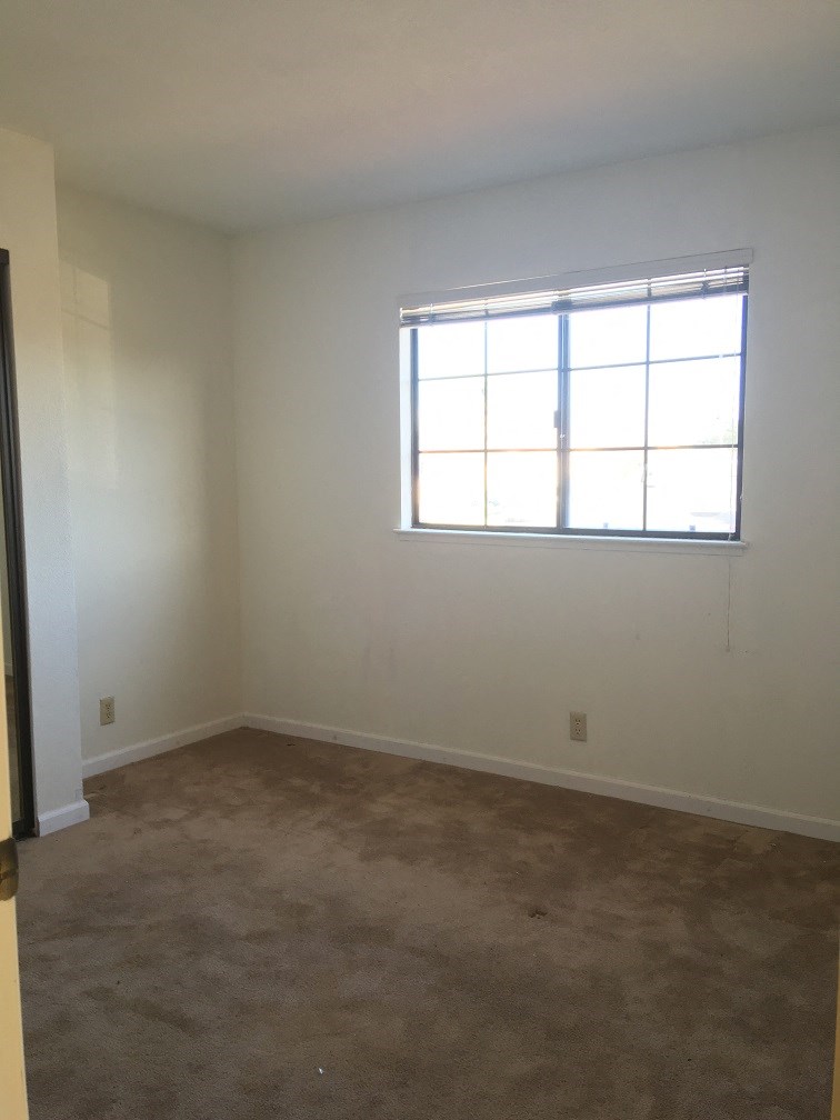 an empty room with a window and a carpet