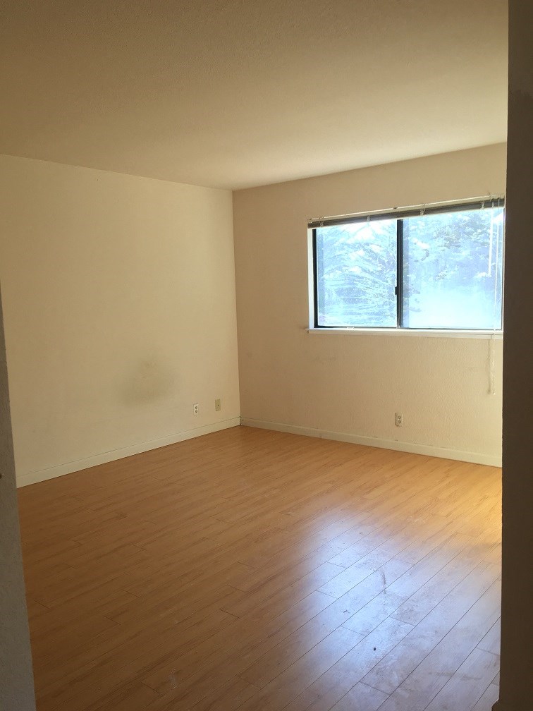 an empty room with a window and wooden floors