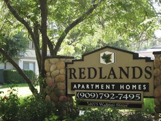a sign for redlands apartment homes in front of a tree