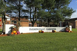 a sign in front of a building with trees and grass