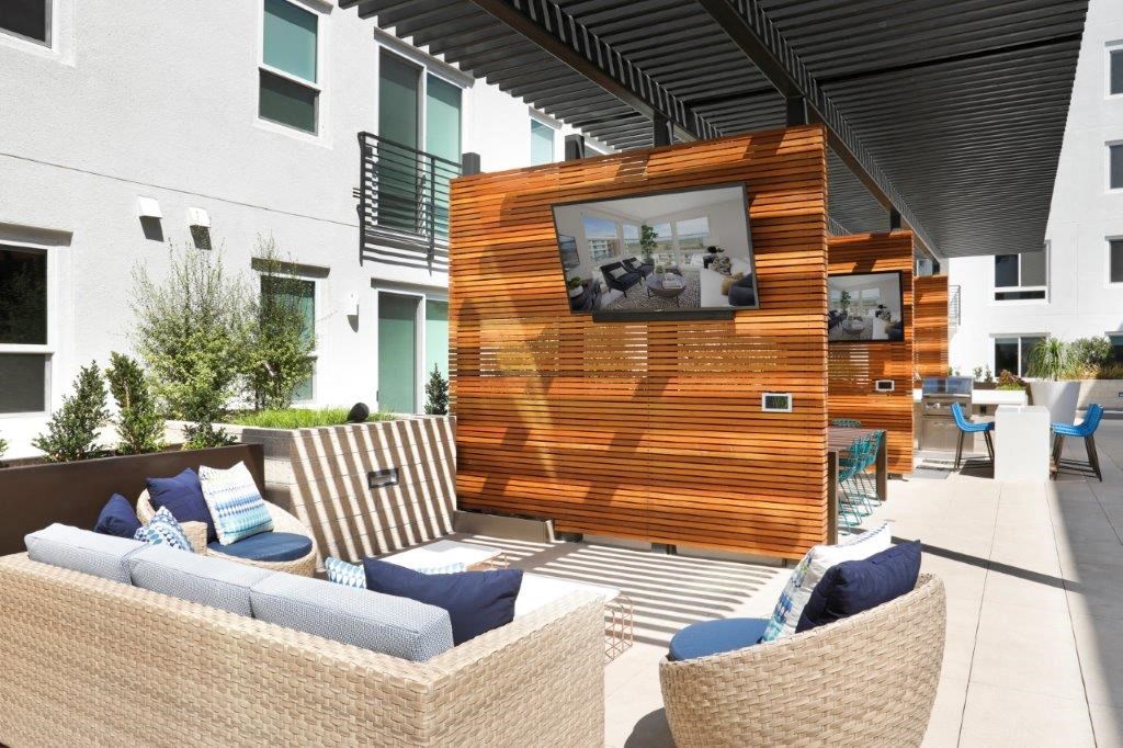 Outdoor patio featuring comfortable furniture and a television for entertainment