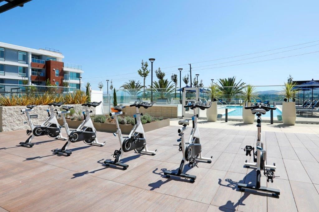 a group of exercise bikes parked on a patio near a pool