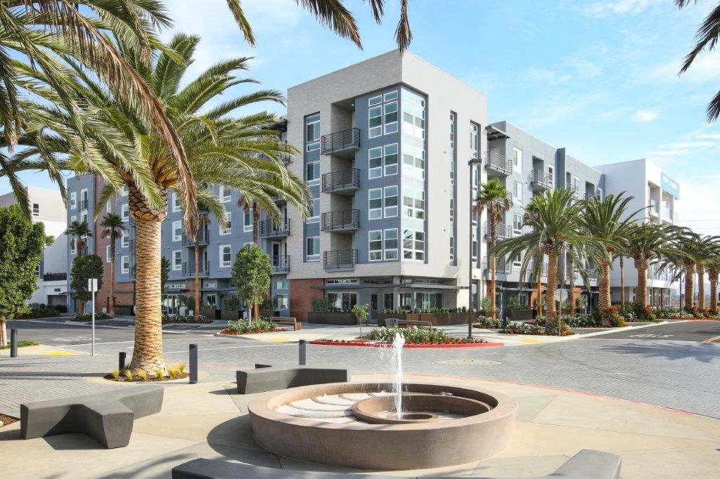 Community entrance with a fountain and palm trees in front of the building