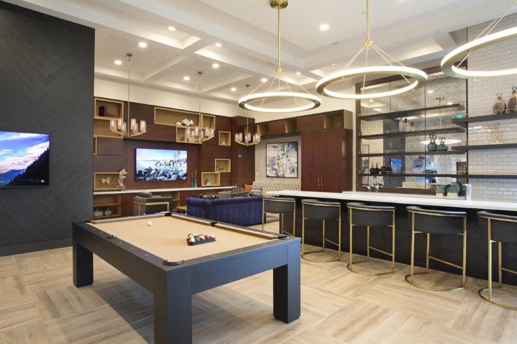 Pool table in a clubhouse featuring a bar and TV for entertainment