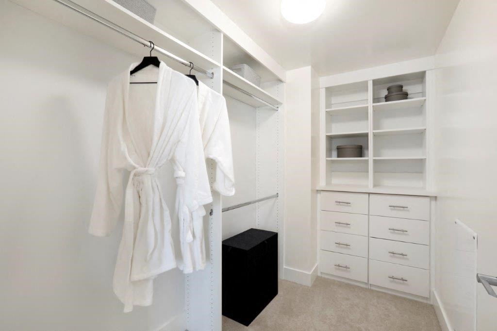 Walk-in closet with white robes and a black dresser.