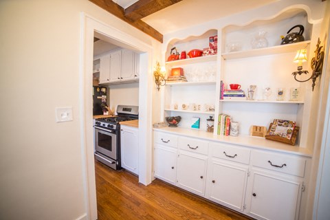 a kitchen with white cabinets and white appliances and shelves