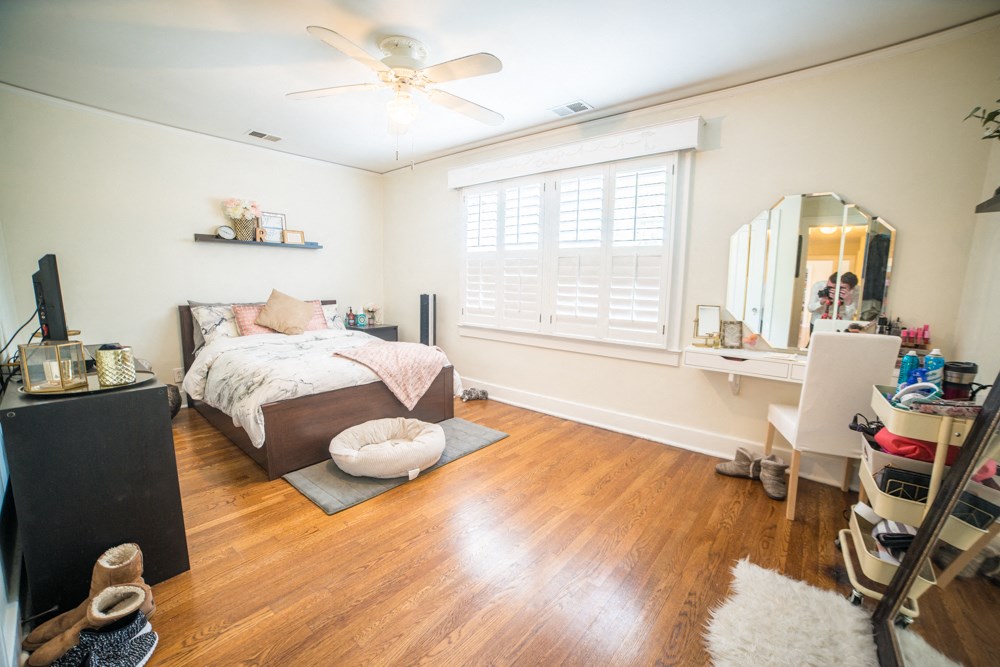 a bedroom with a bed and a desk and a ceiling fan