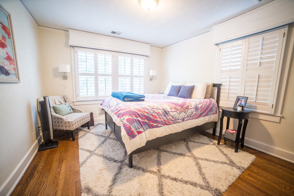 a bedroom with a bed and a chair and a window