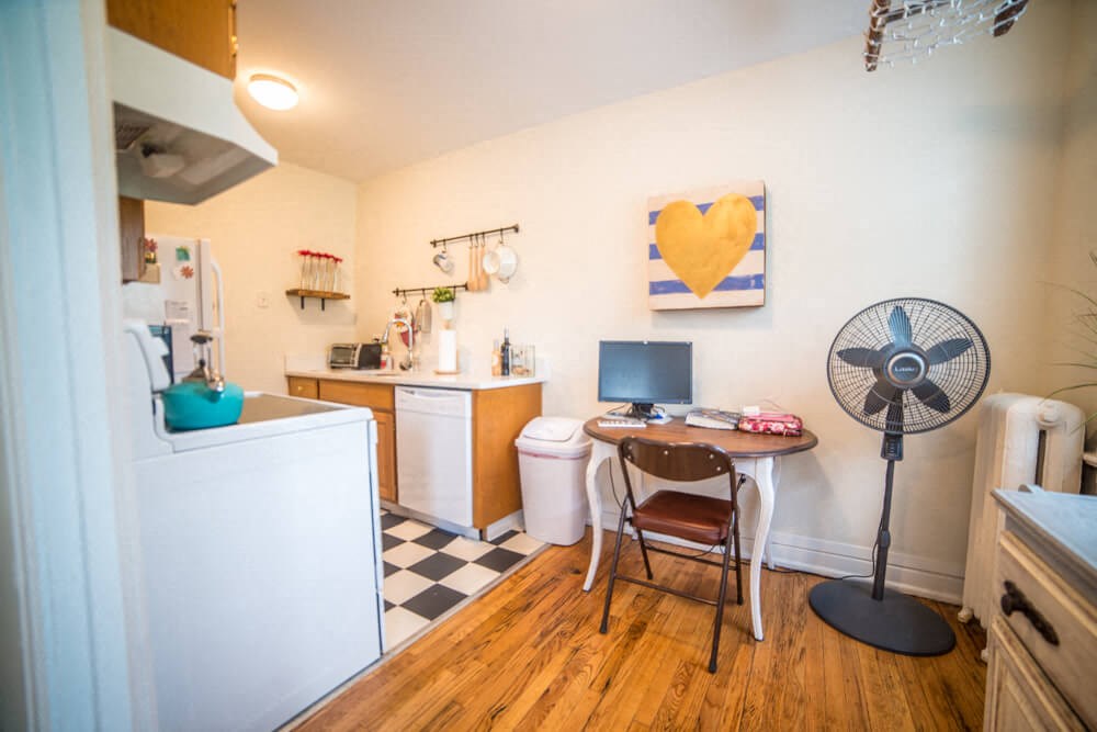a small kitchen with a fan and a desk with a computer