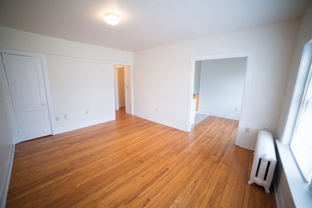 an empty living room with wood floors and white walls