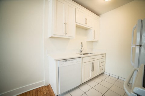 a kitchen with white cabinets and a sink and a refrigerator