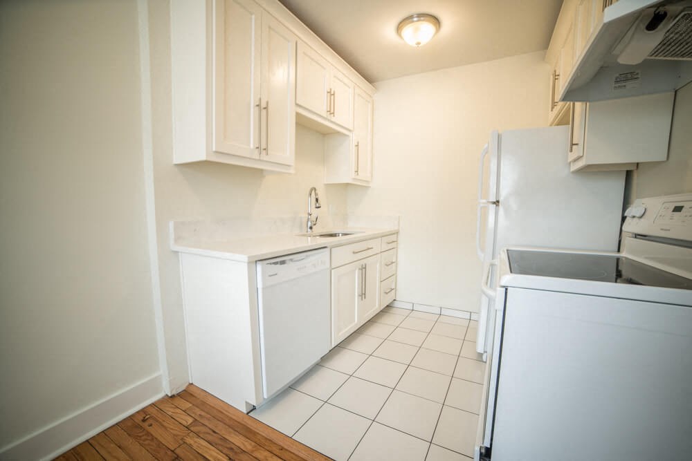 a kitchen with white cabinets and a refrigerator and a sink