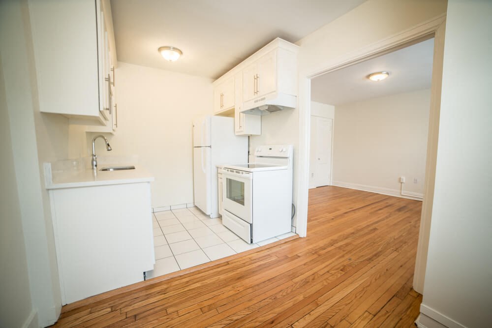 a kitchen with white cabinets and a wooden floor