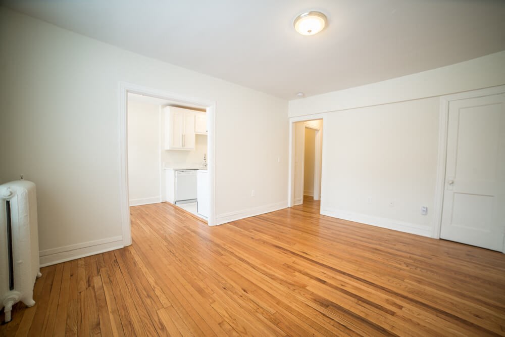 an empty living room with wood flooring and white walls