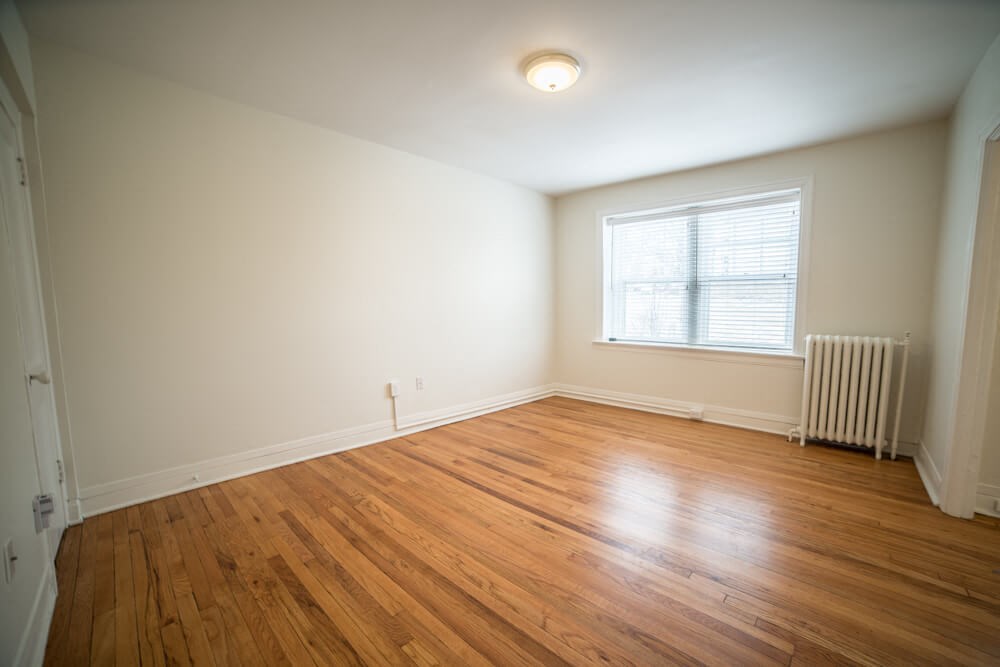 the living room of an empty house with wooden floors and a window