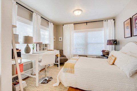 a bedroom with a bed and a desk with a window