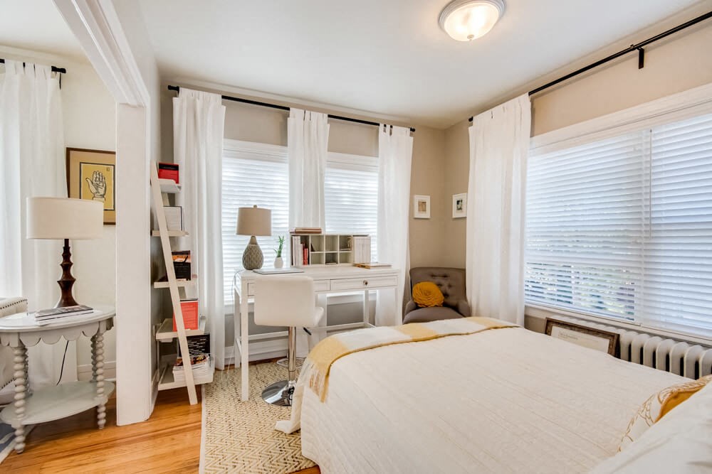 a bedroom with a bed and a desk and windows