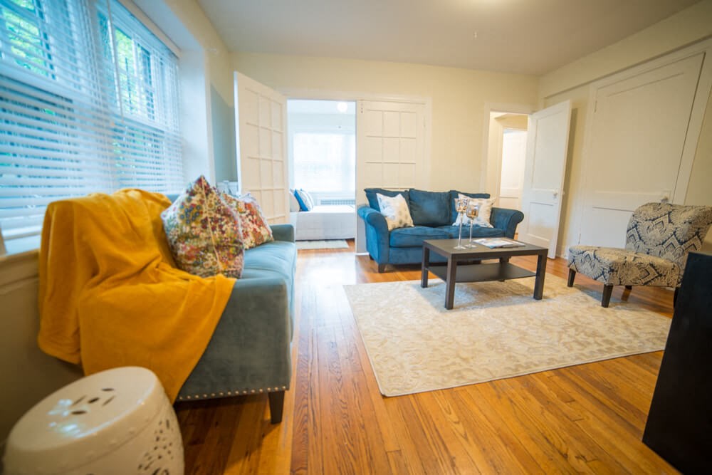 a living room with blue furniture and a yellow blanket on a couch