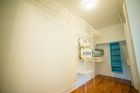 a walk in closet with shelves and a white wall