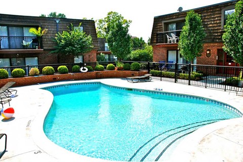 A swimming pool in a residential area surrounded by a black fence.