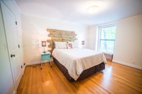 A bedroom with a bed, wooden headboard, and a blue stool.